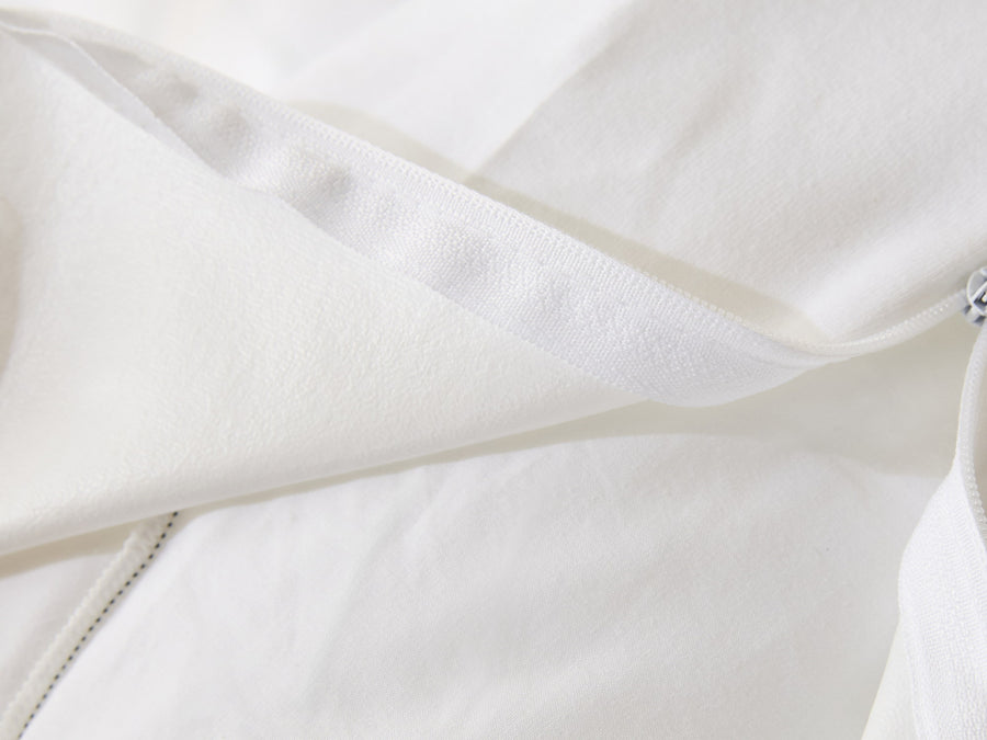 Protège-matelas Serenis : coin replié laissant voir la membrane imperméable sous la face textile