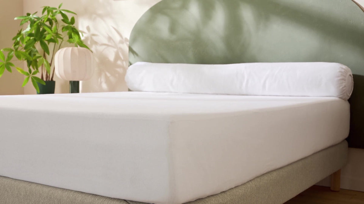 Chambre Serenis — protège-matelas blanc tendu sur le matelas, arche vert sauge